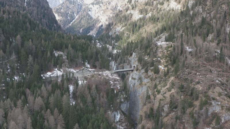 Cars entering the mountain tunnel at the foot of a mountain peak