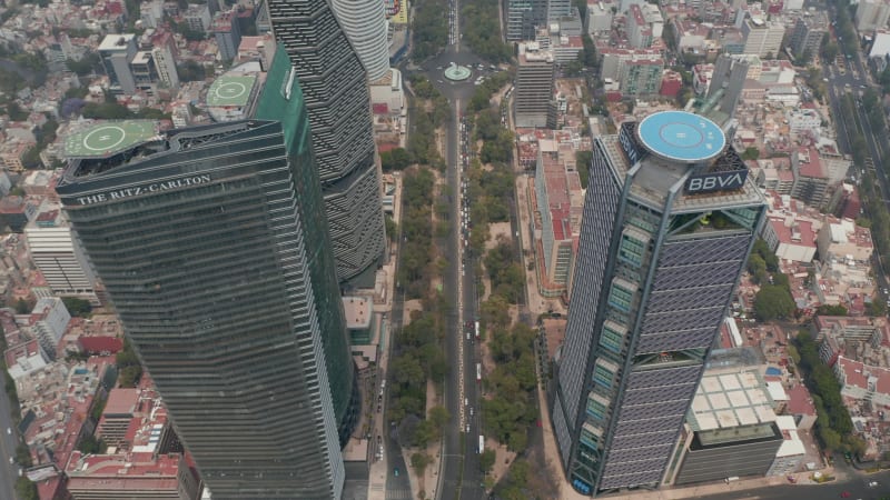 Tilt down view of multilane roads leading between downtown skyscrapers. Aerial view of tall buildings with helipads on roof. Mexico City, Mexico.