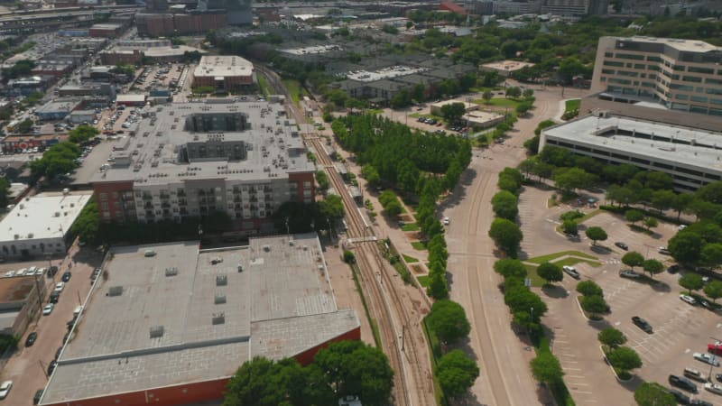 Aerial view of cityscape, tilting up to show downtown panorama. Forward flying drone over railway track. Dallas, Texas, US