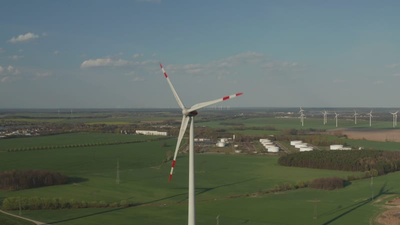 Close up shot of wind Turbine, Mill rotating by the force of the Wind Generating Renewable Energy in a Green Ecologic way for the Planet over beautiful Green Agriculture field