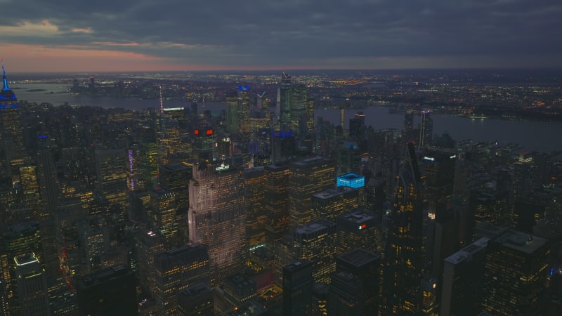 Aerial panoramic footage of downtown high rise buildings in large city at twilight. Lighted windows and colourful rooftops of skyscrapers. Manhattan, New York City, USA