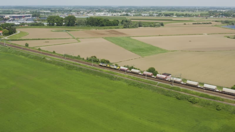 Cargo train traveling through fields toward a city