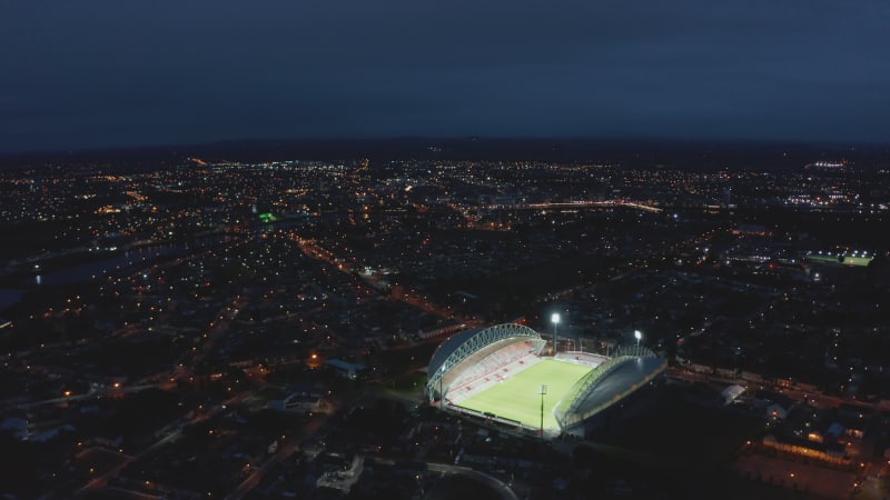 Aerial panoramic view of night city. Bright lights shining on green football playfield. Limerick, Ireland