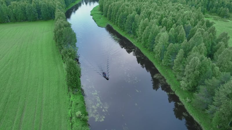 Aerial view of a small boat sailing a river in Overtornea, Sweden.