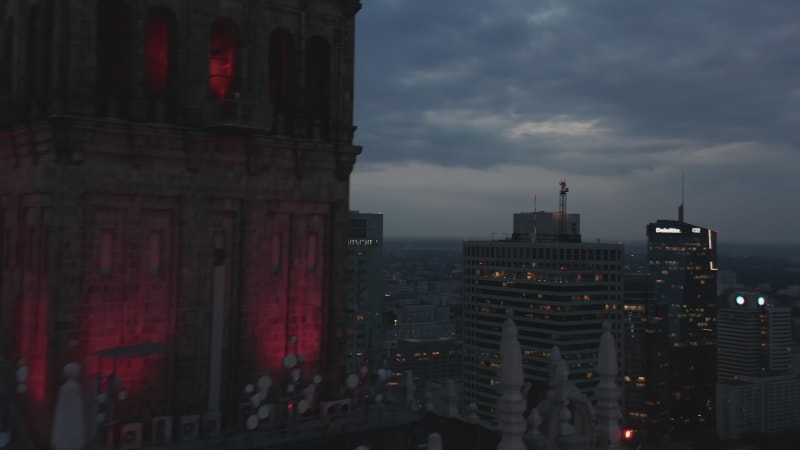 Fly around old high rise decorated building. Revealing evening downtown panorama. Skyscrapers at twilight. Warsaw, Poland