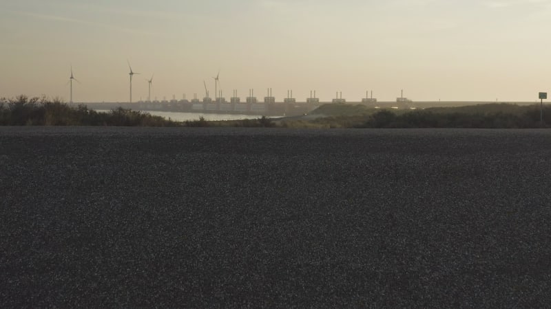 Reveal of the empty sandy beach with wind turbines and storm protection in the back.