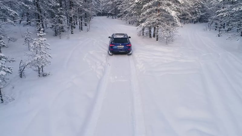 Aerial view of a car driving in the snowy forest.