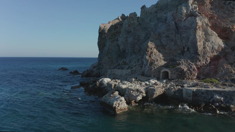 Old Abandoned Mine entrance Tunnel in a Mountain at Beach on Milos Island, Greece Aerial View at Sunset