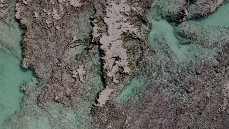 Aerial view of remote beach tidal pool man walk, Western Cape, South Africa.