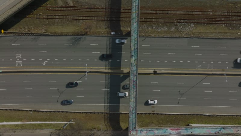 Top down panning footage of cars driving on multilane highway along railway track. Various colour vehicles. Boston, USA