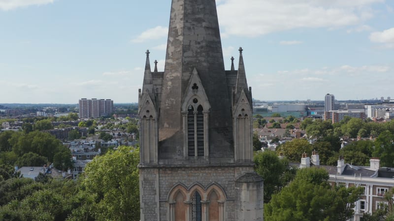 Pull back footage of church spire. Tower of gothic building in park. Elevated view of urban borough. London, UK