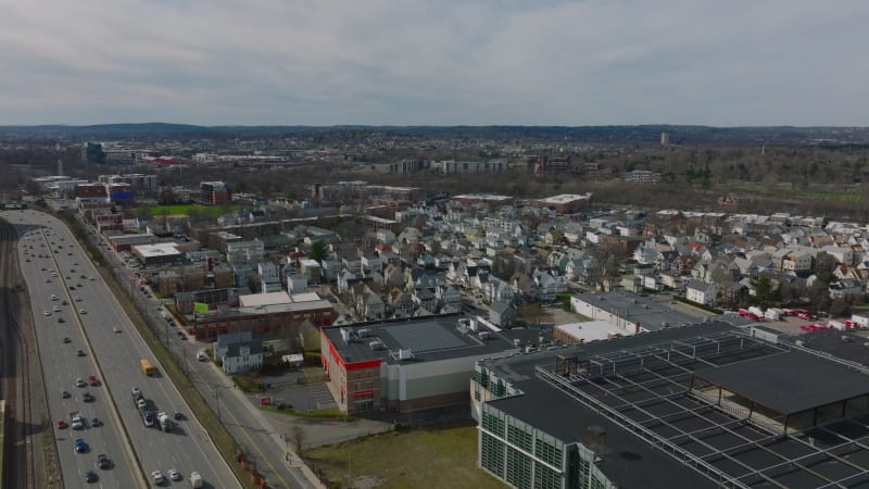 Aerial shot of residential neighbourhood at busy highway. Rows of houses and apartment buildings along streets. Boston, USA