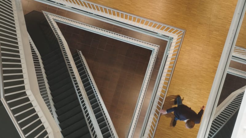 Top down aerial shot of a hallway and escalators at the Galgenwaard stadium at FC Utrecht, with people walking down