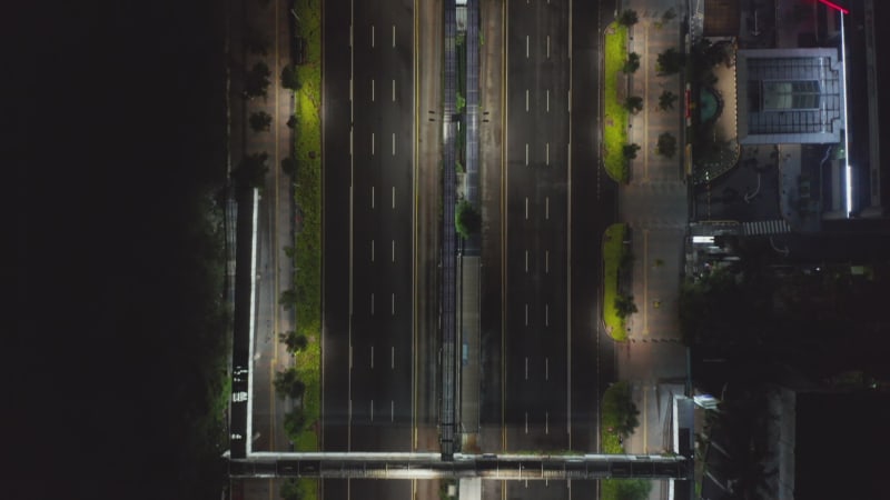 Top down overhead aerial view of empty multi lane motorway at night during coronavirus lockdown in modern city center