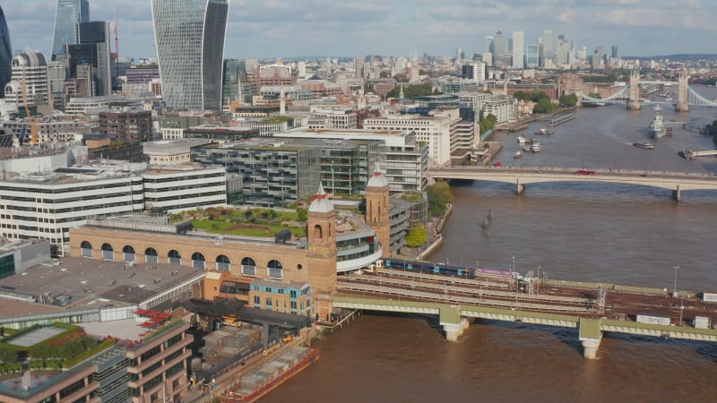 Tilt and pan footage of Cannon Street train station. Trains standing at platforms in station on waterfront. Aerial view of riverside. London, UK