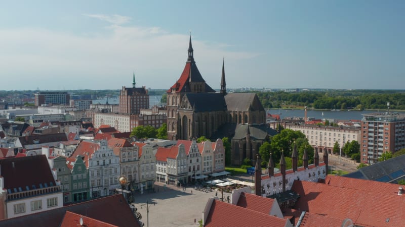 Fly over historic city centre, square with old typical colourful gabled houses. Orbiting around Saint Marys church. Large brick gothic