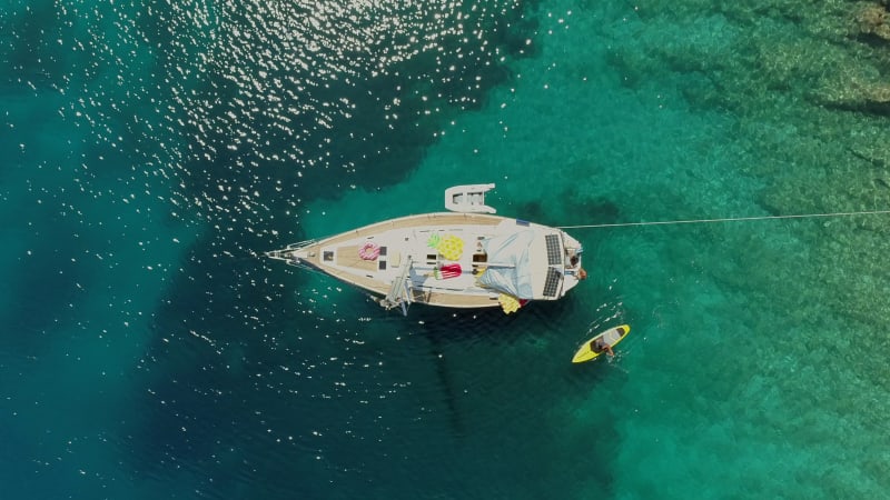 Aerial view of paddle board next to boat anchored on the coast of Varko.