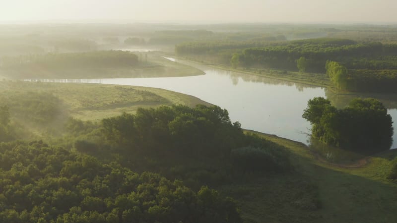 Rising aerial establishing shot of wetlands and lakes with mist and golden light in Holland