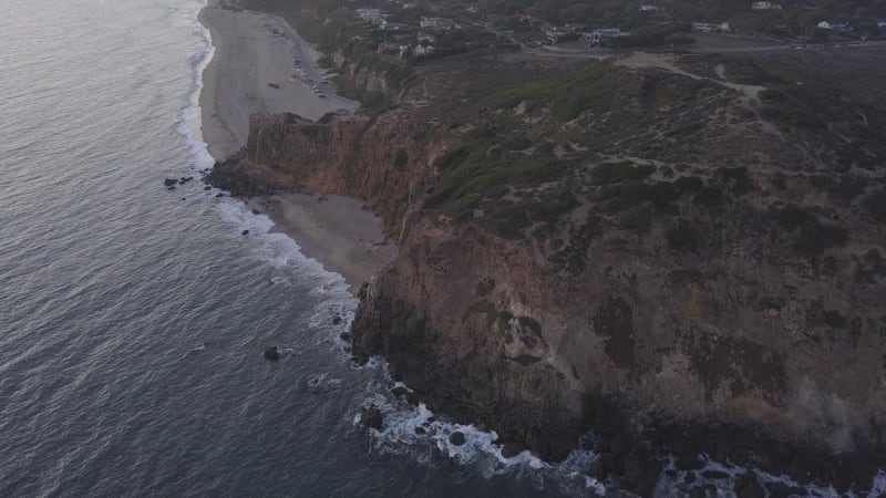 AERIAL: flight over Malibu, California view of beach Shore Line Pacific ocean at sunset with mountain cliff