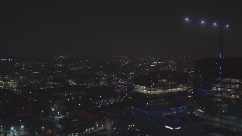 Forwards reveal of night city. Aerial view of streets and building lit by electric lights. Dallas, Texas, US