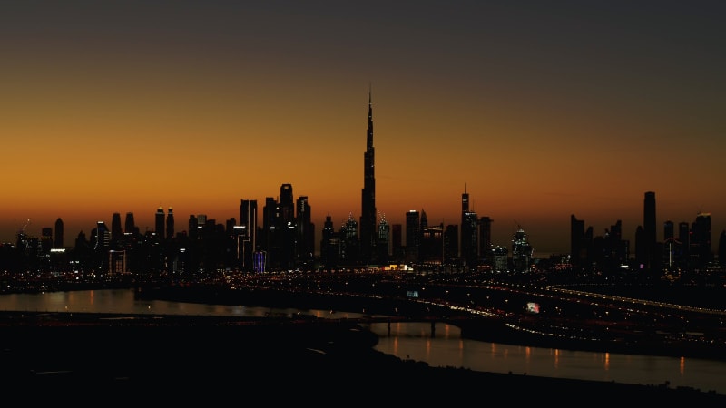 Aerial view of Dubai skyscrapers silhouettes at sunset.