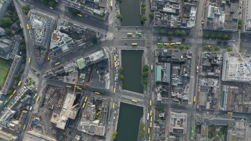 Aerial birds eye overhead top down panning view of town with river. Lot of yellow bus roofs in streets. Dublin, Ireland