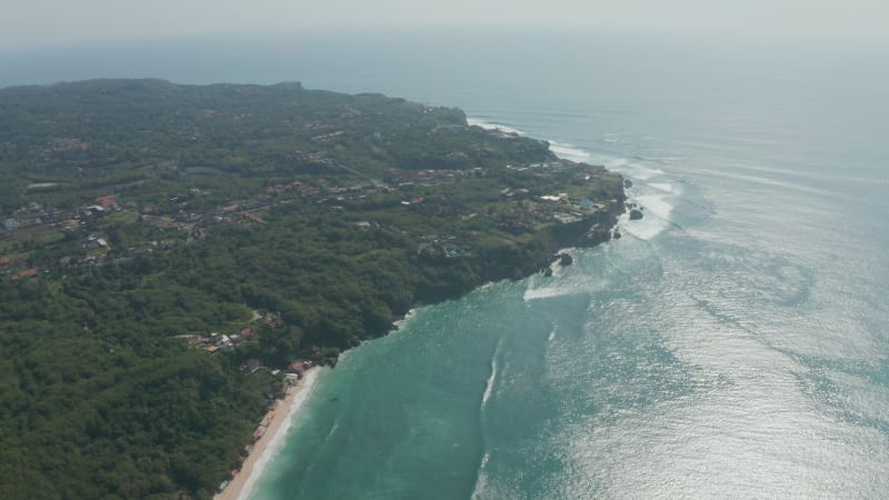 Aerial view of luxury houses on tropical coastline of Bali. Panoramic view of Bali coastline with lush green vegetation and sandy beaches by the ocean