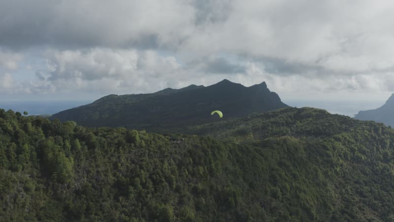 Aerial view of a person doing paragliding among the mountain, Mauritius.