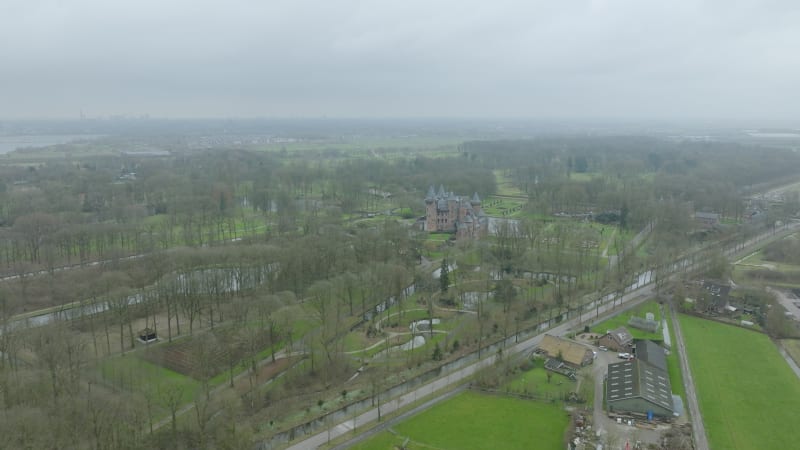 Wide shot flying towards a Dutch Castle in Utrecht, The Netherlands between the trees and garden during cloudy fall day