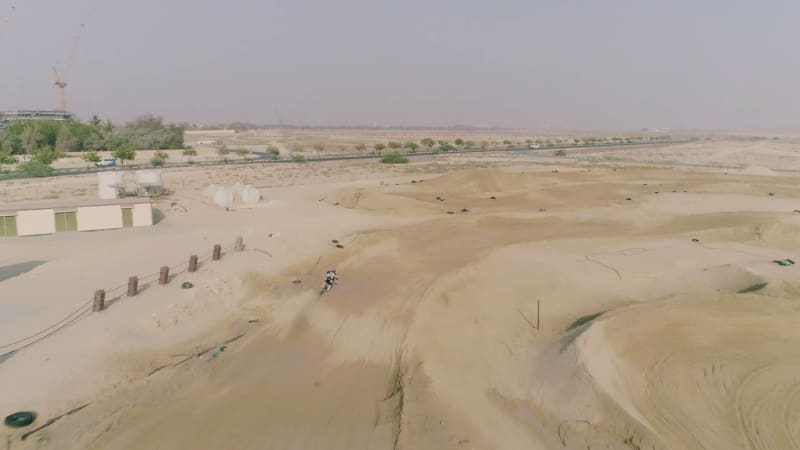 Aerial view above of man practicing motocross at desert landscape.