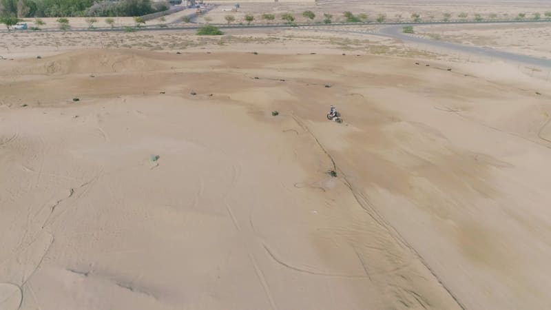 Aerial view of man practicing circuit motocross at desert landscape.