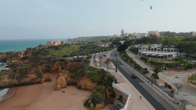 Amazing aerial drone view of Portuguese coastline, drone flying sideway above road in Lagos reveal tourist attraction beaches, Algarve, day