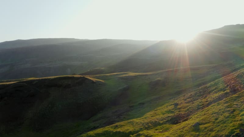 Amazing birds eye slider backlight view of Iceland grassland landscape. Beauty in nature. Drone view of spectacular panorama with geothermal steaming fumaroles in background