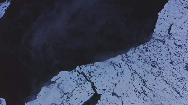 Fog moving over snow covered rock and lake in Norway.