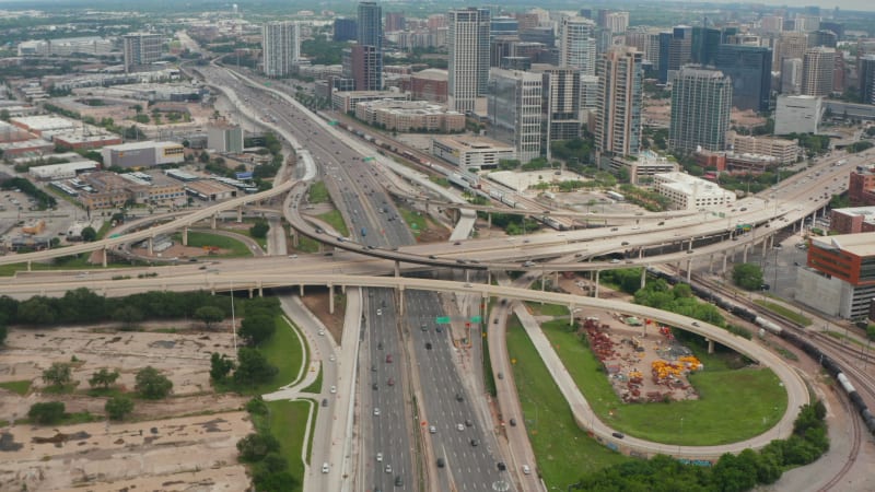 Forward flying drone towards huge multi lane highway intersection in town. Aerial view of traffic at rush hour. Tilt down to detail of multilevel transport construction. Dallas, Texas, US