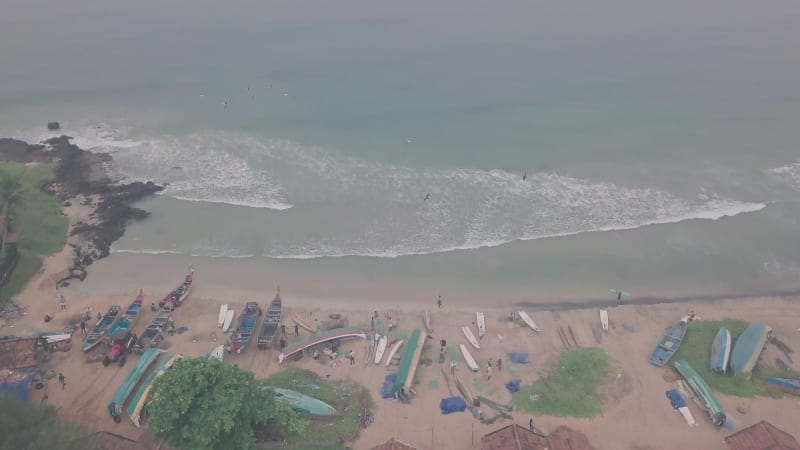 Fishermen on the beach and people swimming in the ocean by a sandy beach