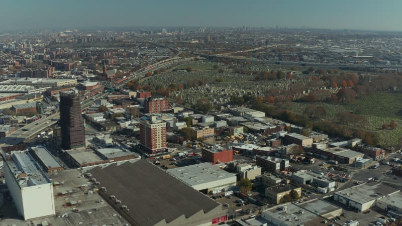 Forwards fly above suburbs. Area around historic large Calvary Cemetery. Busy multilane trunk road leading along. Queens, New York City, USA