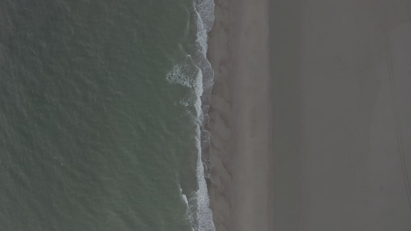 Generic Brown Beach Pattern and Dark Green Ocean on Cloudy Day, Top Down Overhead Aerial Birds Eye View