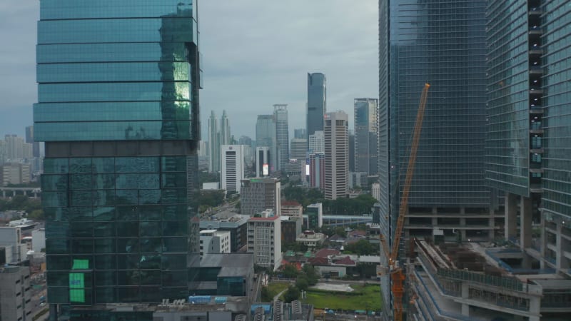 Aerial forward flight towards downtown city skyscrapers between two glass skyscrapers in Jakarta, Indonesia