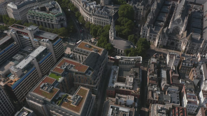 Aerial view of multistorey buildings in town and traffic in streets. Tilt up of cars and buses driving through road intersection. London, UK