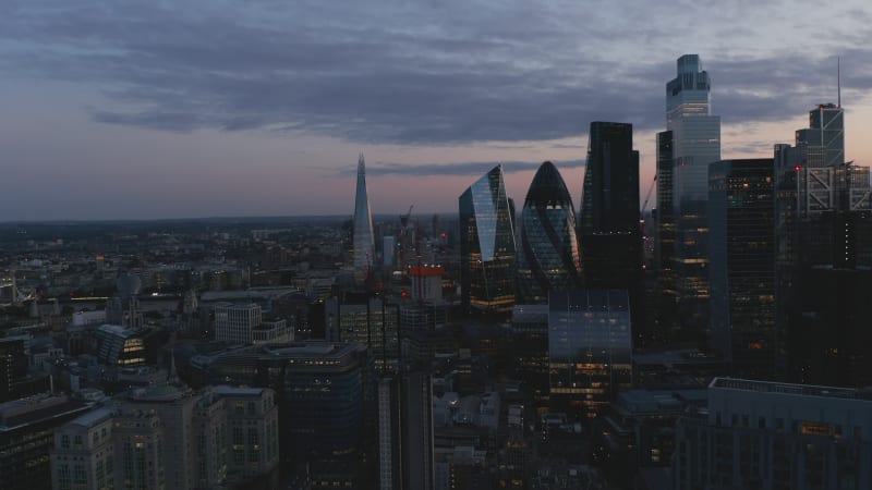 Evening elevated footage of tall modern skyscrapers against twilight sky. Office buildings in business hub. London, UK