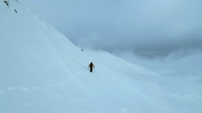 Mountaineer Walking Through Deep Snow During Ascent on a Mountain