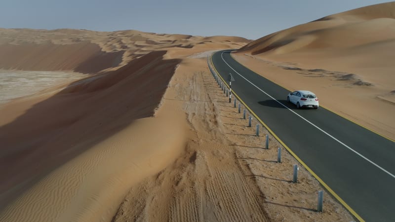 Aerial view of white car in clean road in the desert.