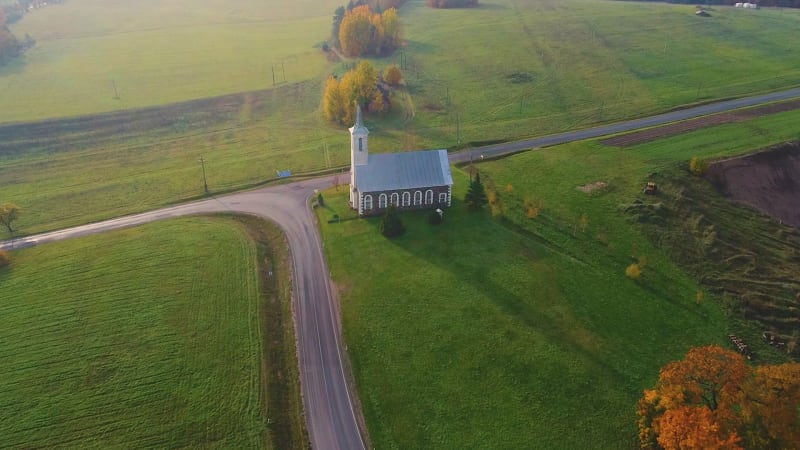 Aerial view of an isolated church near the road.