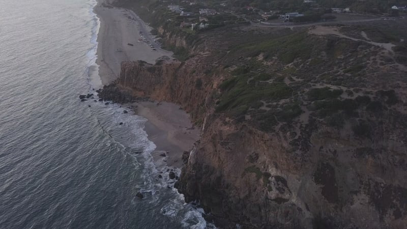 Mountains at Pacific ocean with waves crashing on cliff in Sunset light, Aerial Wide Angle