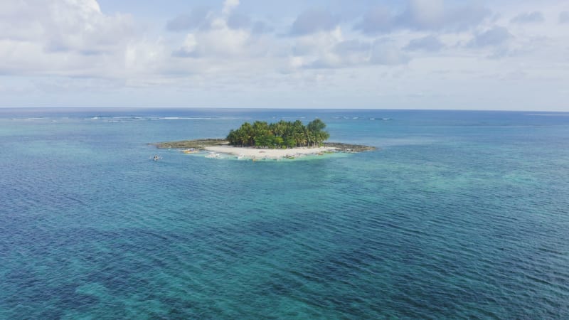 Isloated island in clear turquoise water with people on beach