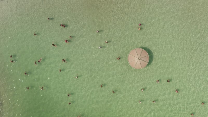 People floating in The Dead Sea, The lowest place on earth, known for its extremely high concentration of dissolved mineral salts.