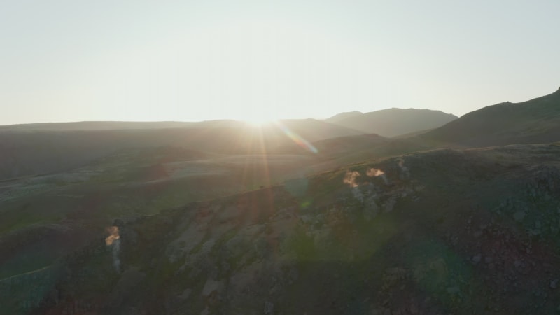 Drone point of view of spectacular highlands in Iceland. Aerial view flying over steaming rocky formations at sunset in backlight