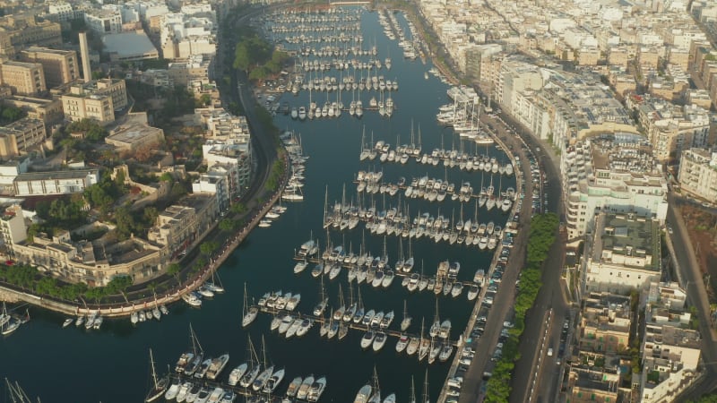 Sailboats and regular Boats sitting in Marina Port on Malta Island, Aerial tilt down View