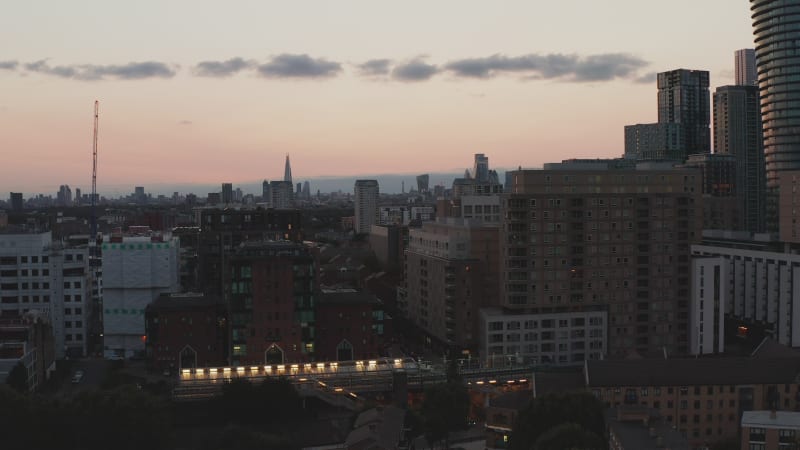 Evening landing footage at street in town. Cityscape gradually hiding behind buildings. Colourful sky after sunset. London, UK